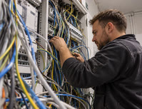 Elektriker vor einer Wand voller Kabelbuendel