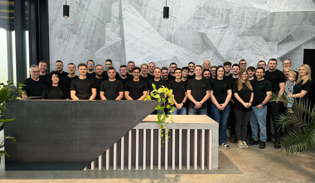 Das [tecbox]-Team im Büro vor der Wandmalerei
